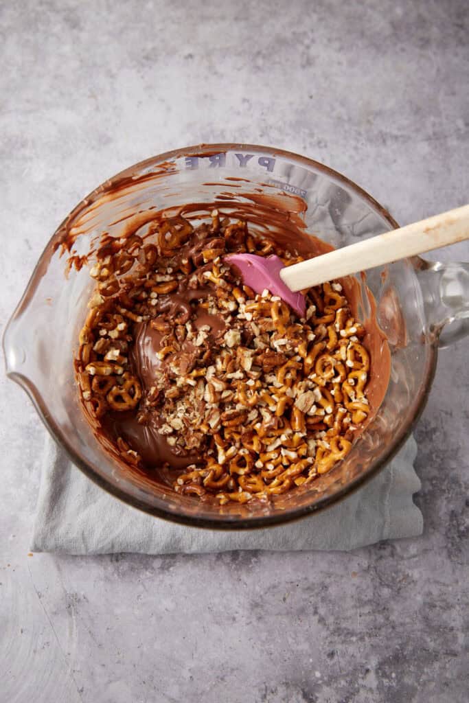 pecans and pretzels being folded into a chocolate mixture.