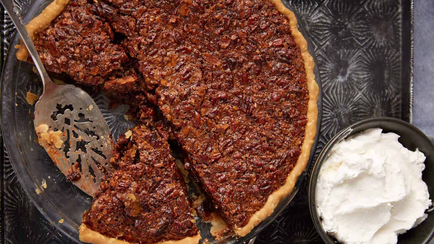 A piece of pecan pie being removed from a pie dish.