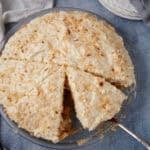 a slice of coconut cream pie with a slice being taken out of it.