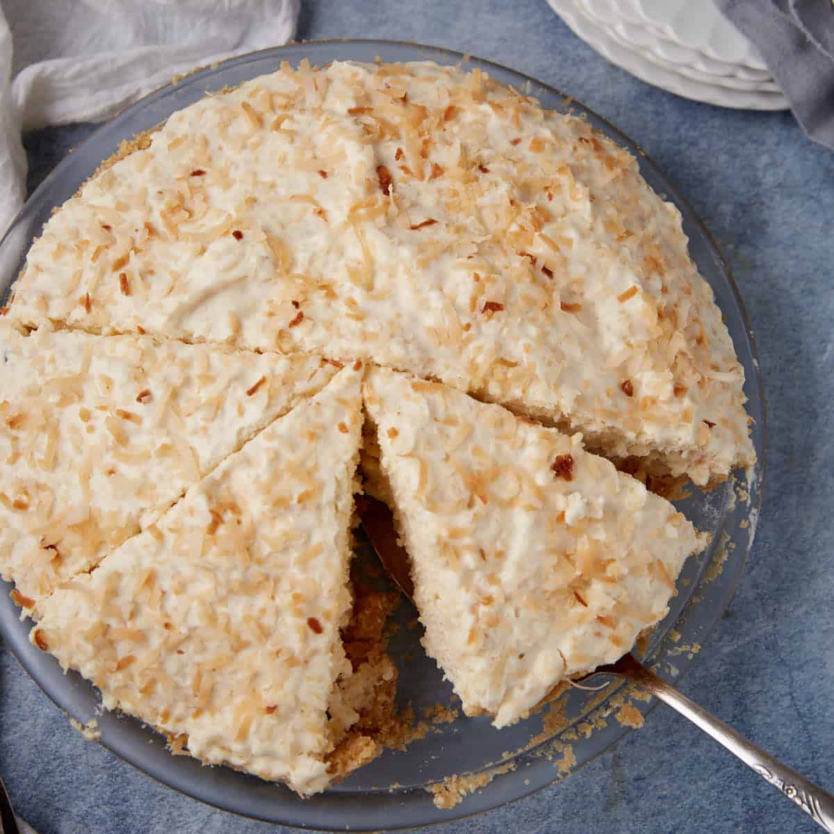 a slice of coconut cream pie with a slice being taken out of it.