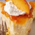 slice of peach cheesecake on a white plate with a bite taken out of it.