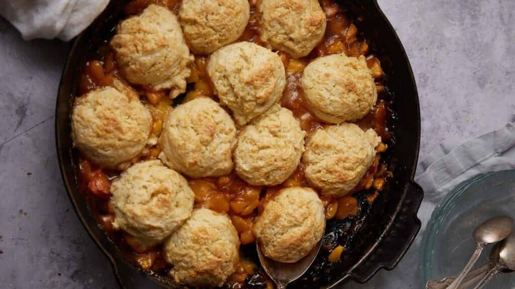 peach cobbler with biscuits in a skillet.