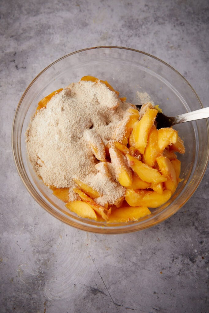 ingredients for peach filling in a glass bowl with a spoon.