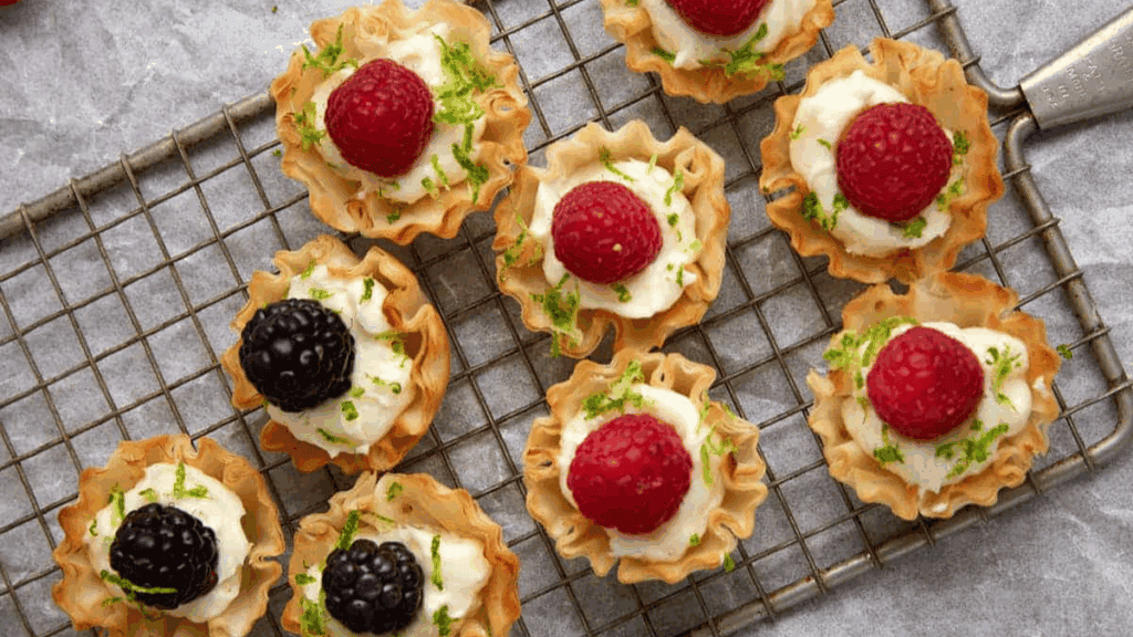 raspberry tarts lined up on a cooling rack.