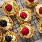 raspberry tarts lined up on a cooling rack.