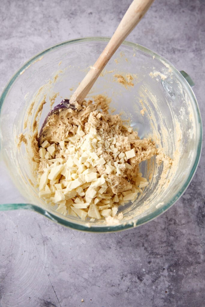 chopped white chocolate being folded into cookie dough.