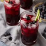 blueberry lemonade in glasses garnished with lime slices.