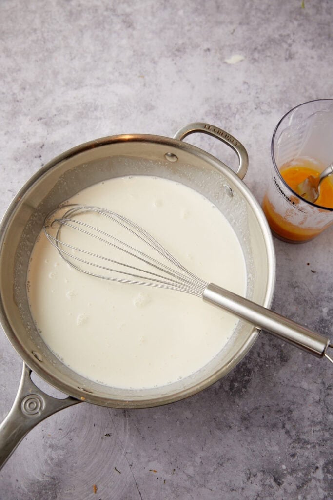 milk being heated up and whisked in a saucepan.