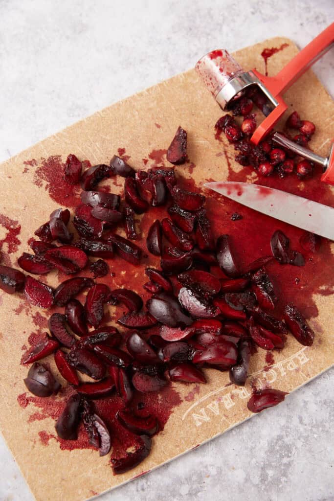 chopped cherries on a wooden cutting board with a knife.