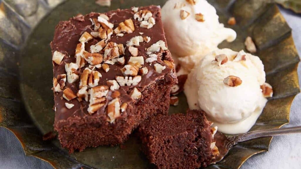 A piece of chocolate cake next to scoops of ice cream.