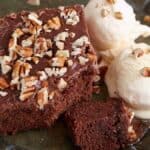 A piece of chocolate cake next to scoops of ice cream.