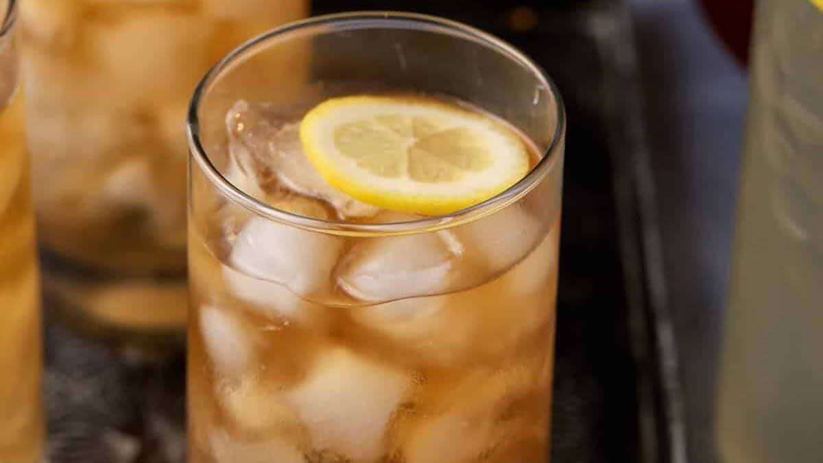 Iced tea lemonade with ice cubes and lemon wedges.