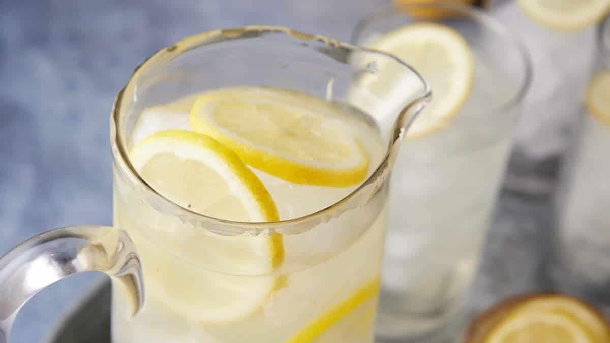 Homemade lemonade poured into a glass with lemon slices and ice.