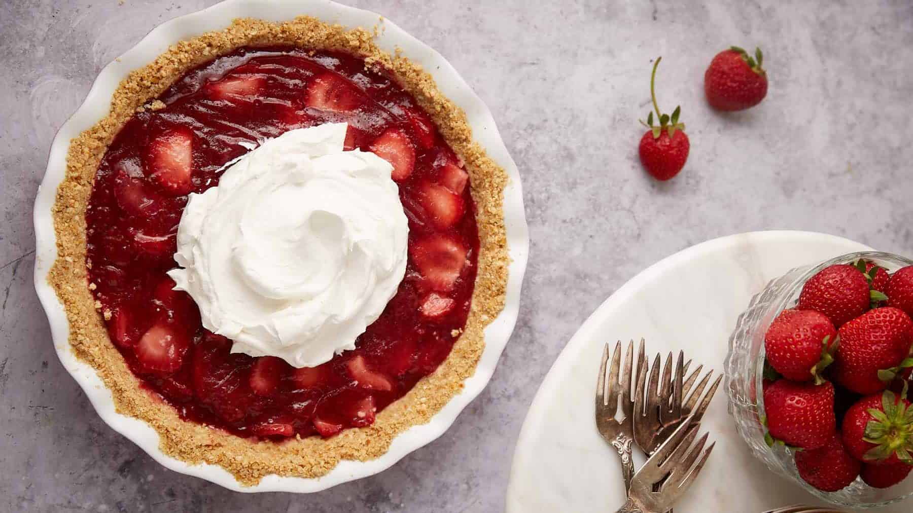 A strawberry pie topped with whipped cream.