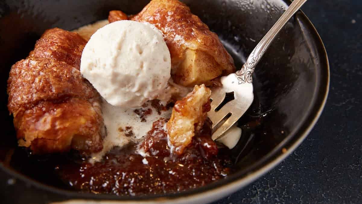 Ice cream on top of a hot apple dumpling in a bowl.