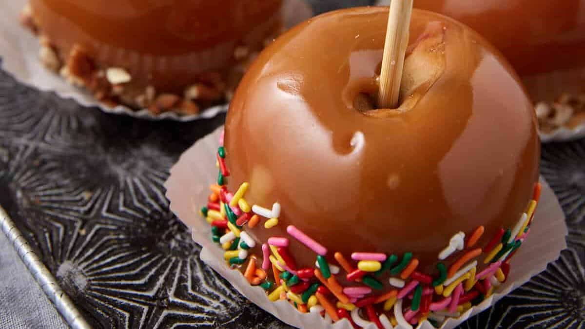 caramel apples on a tray dipped in sprinkles.