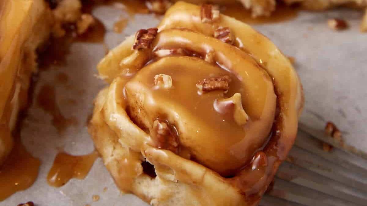 A single caramel pecan cinnamon roll on parchment paper.