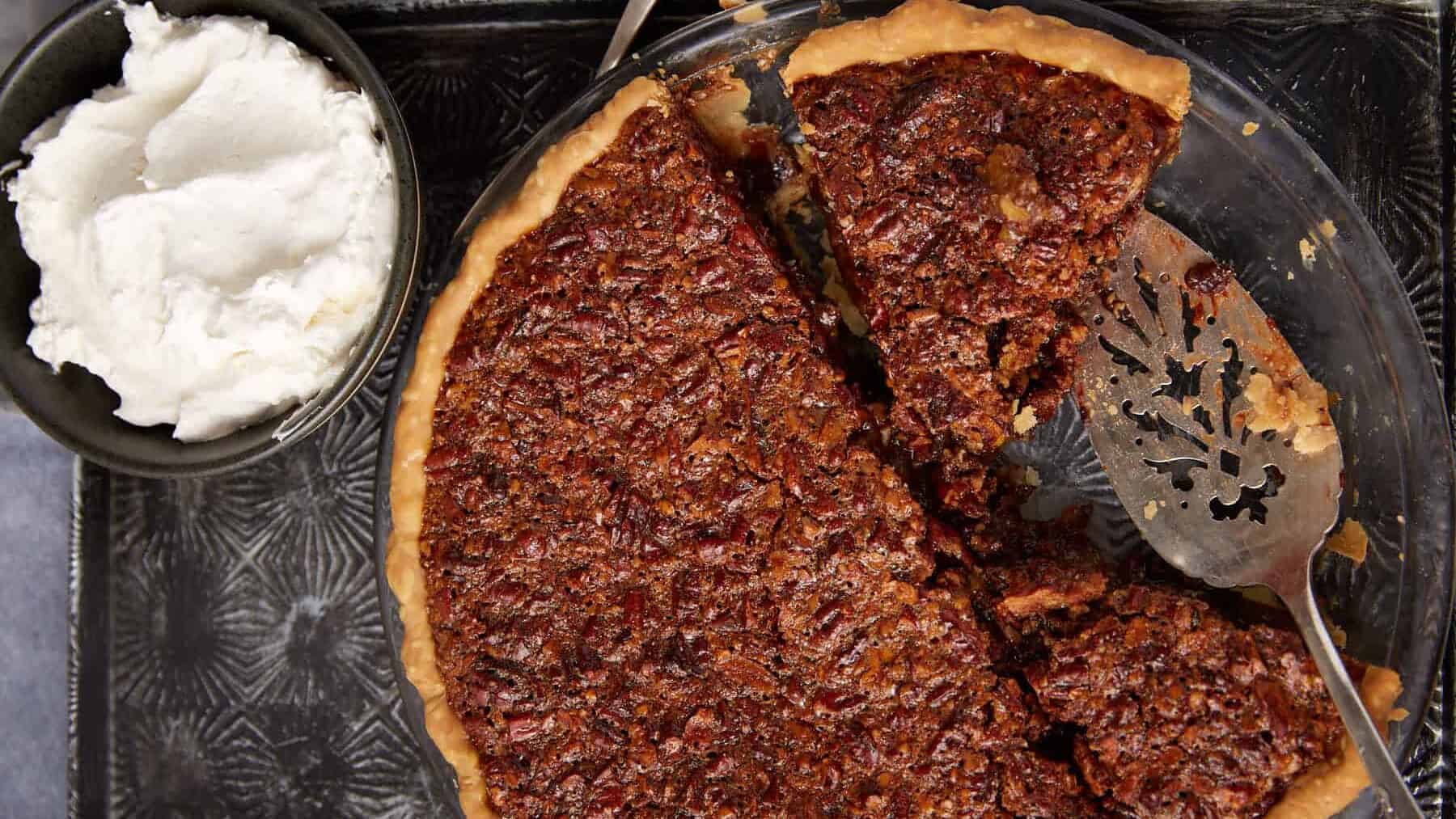 A piece of pecan pie being removed from a pie dish.