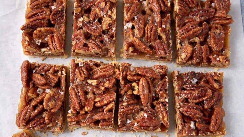 pecan pie bars sliced onto parchment paper.