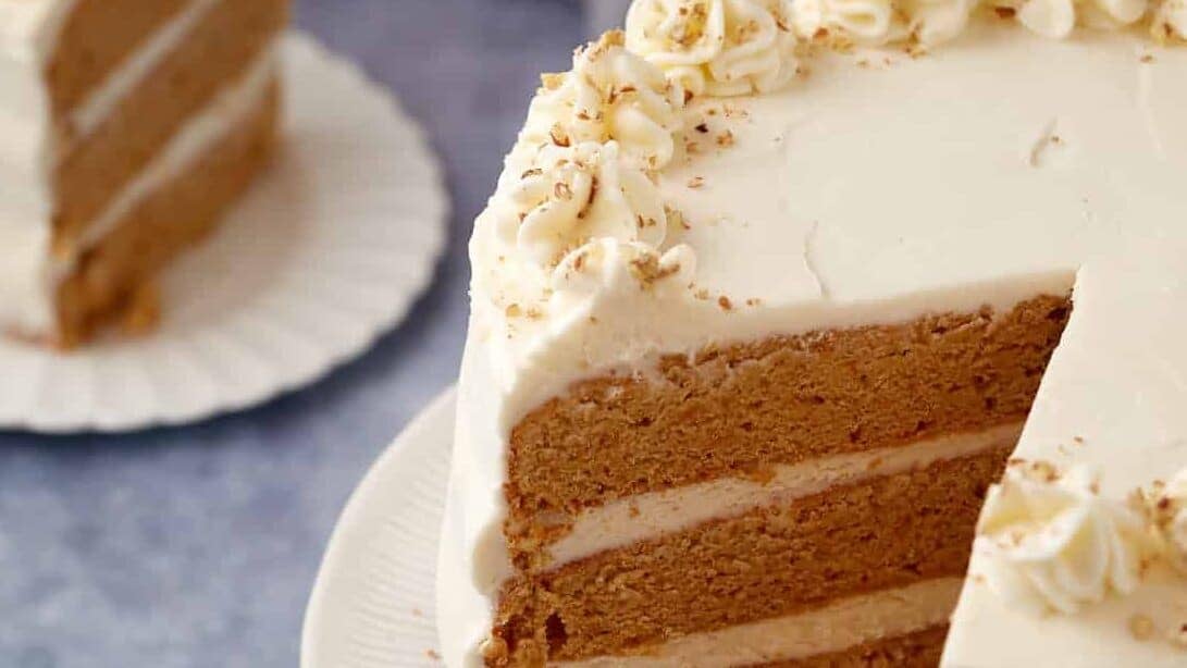 A frosted sweet potato cake with a wedge removed.