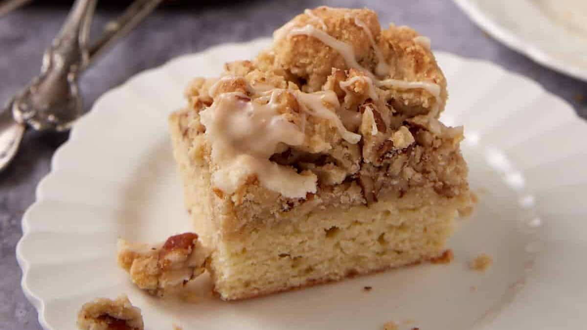 piece of crumb cake on a white plate with forks.