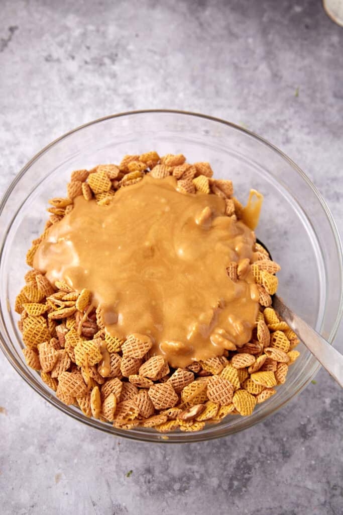 Warm caramel sauce poured over a large bowl of Crispix cereal and pecans.