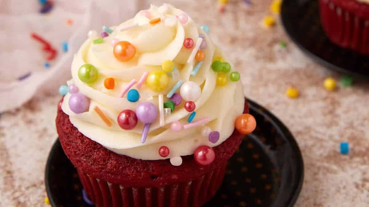 Three cupcakes with cream cheese frosting and sprinkles.