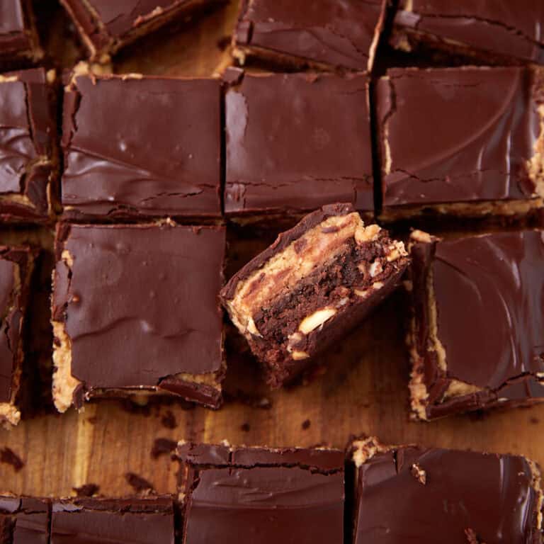 A full sheet of peanut butter brownies cut into squares, with one brownie turned on its side to show the layered interior.