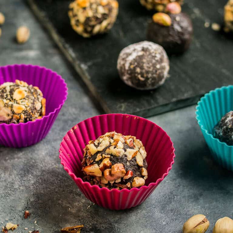 Chocolate truffles rolled and placed in colorful silicone candy cups with assorted coatings.