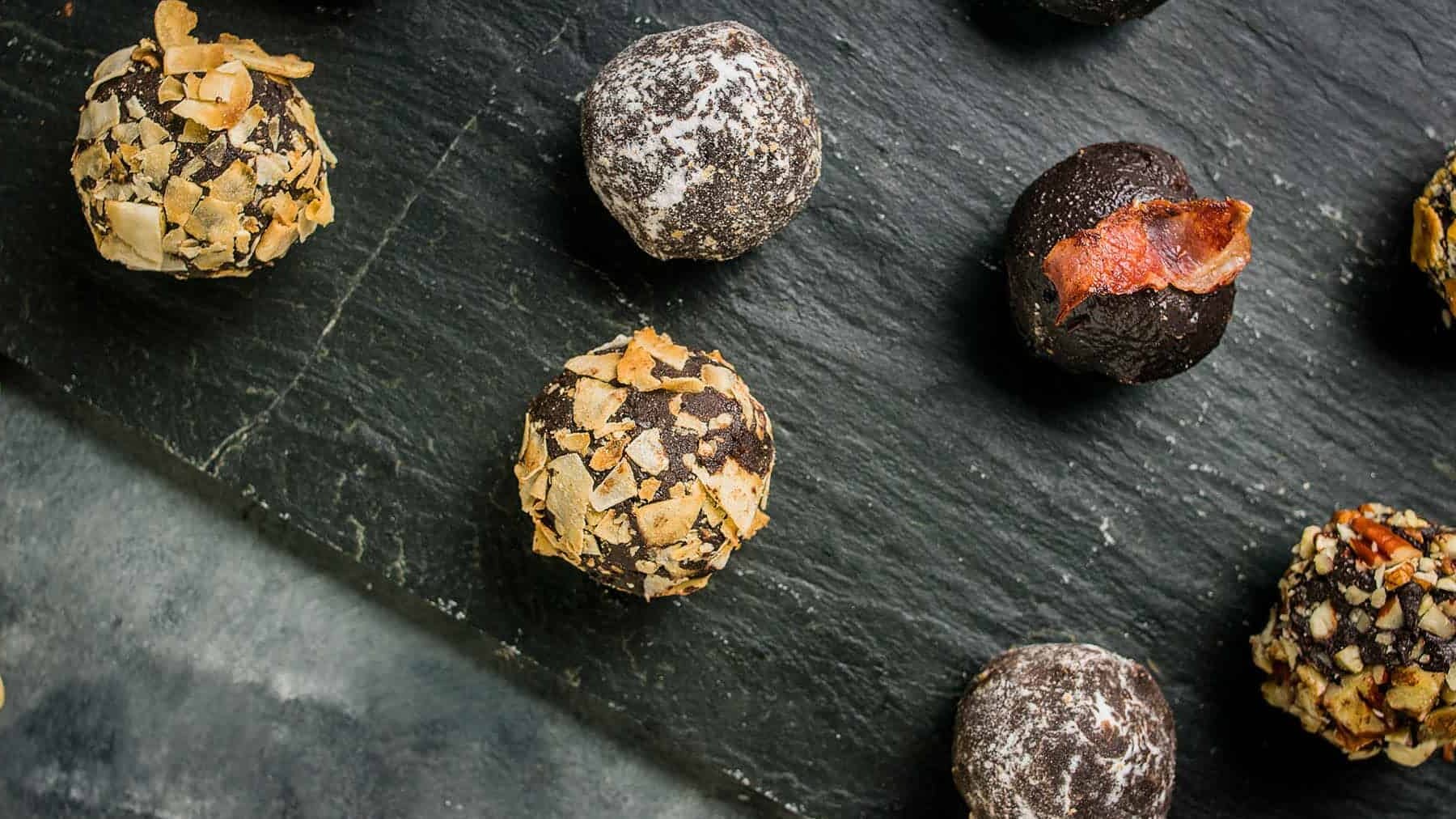 Close-up of chocolate truffles showing different coatings including chopped nuts and powdered sugar.