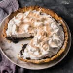 Close-up overhead shot of a chocolate meringue pie with a large slice removed.