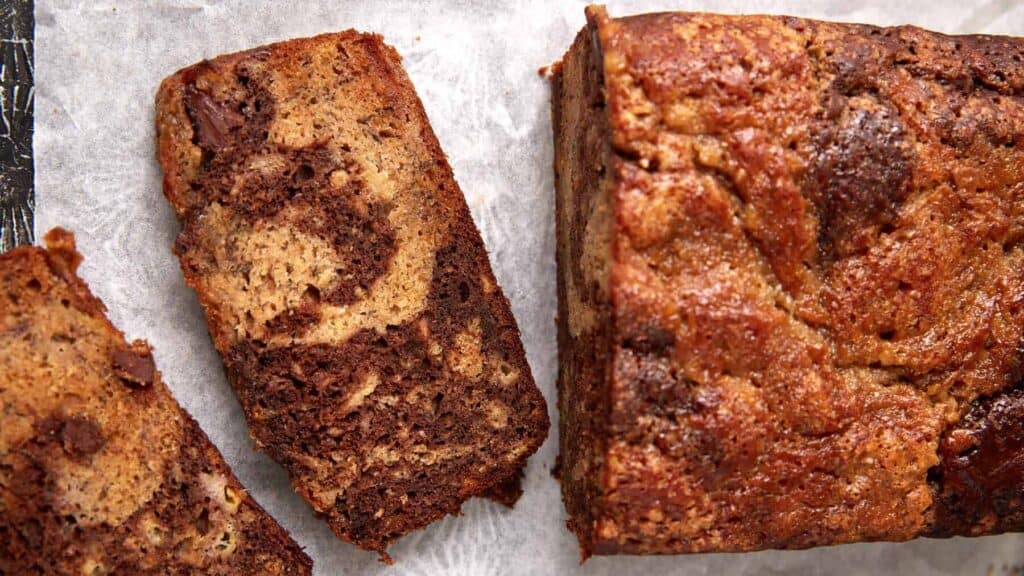 Chocolate banana bread loaf with a couple of slices cut, showing the marbled pattern and moist texture.