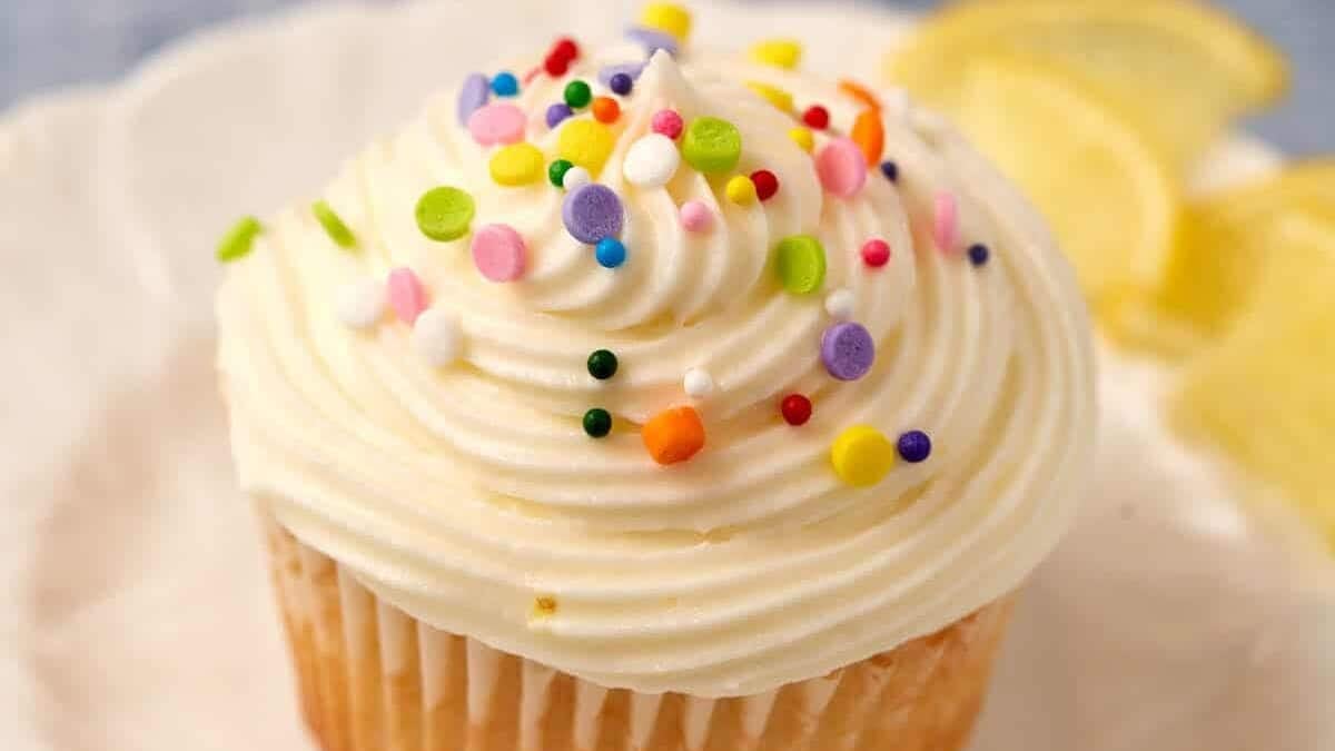 A single lemon cupcake with sprinkles on a plate.