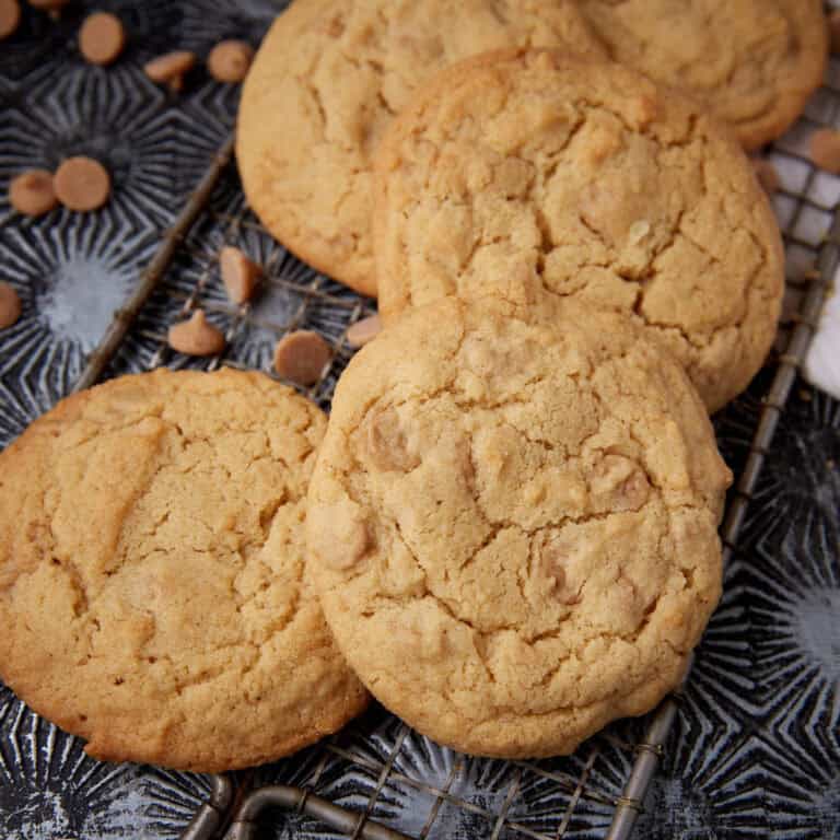 Overhead shot of four Reese&rsquo;s peanut butter cookies arranged closely together on a cooling rack, showing their crackly, golden tops.
