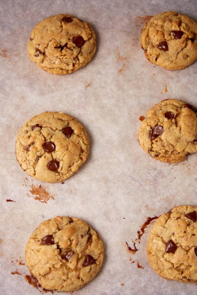 Sheet of freshly baked toffee chocolate chip cookies cooling on parchment paper.