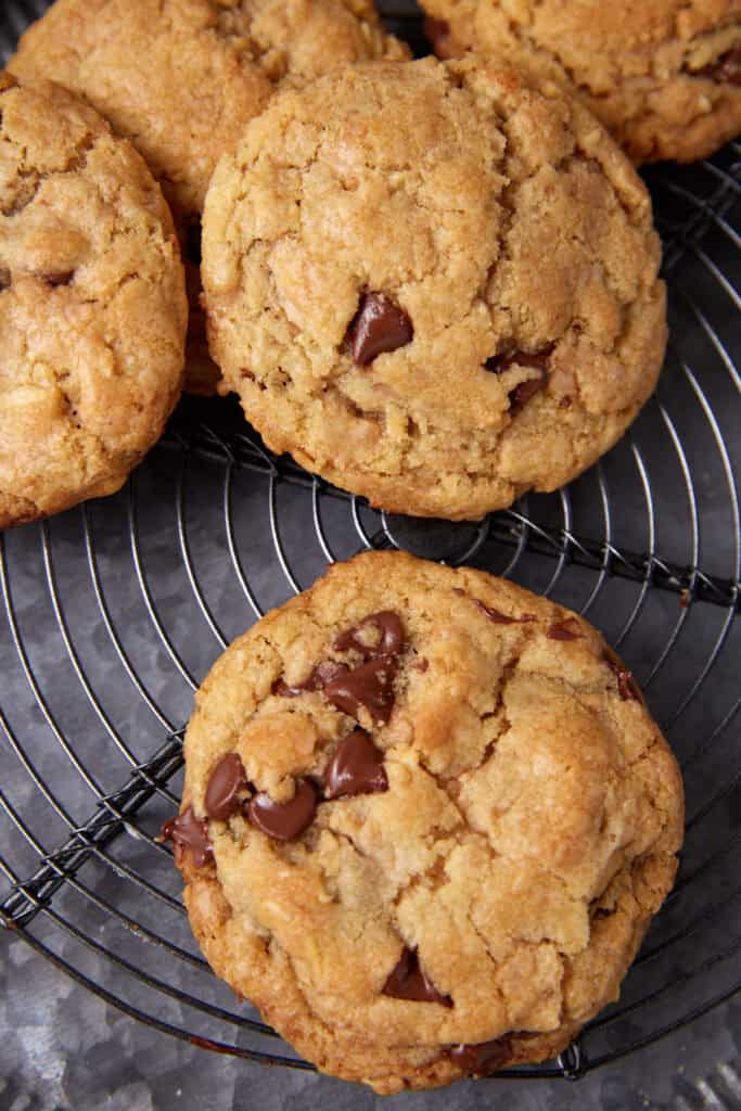 Close-up of toffee chocolate chip cookies on a wire cooling rack, showing the cracked tops and visible chocolate chips.