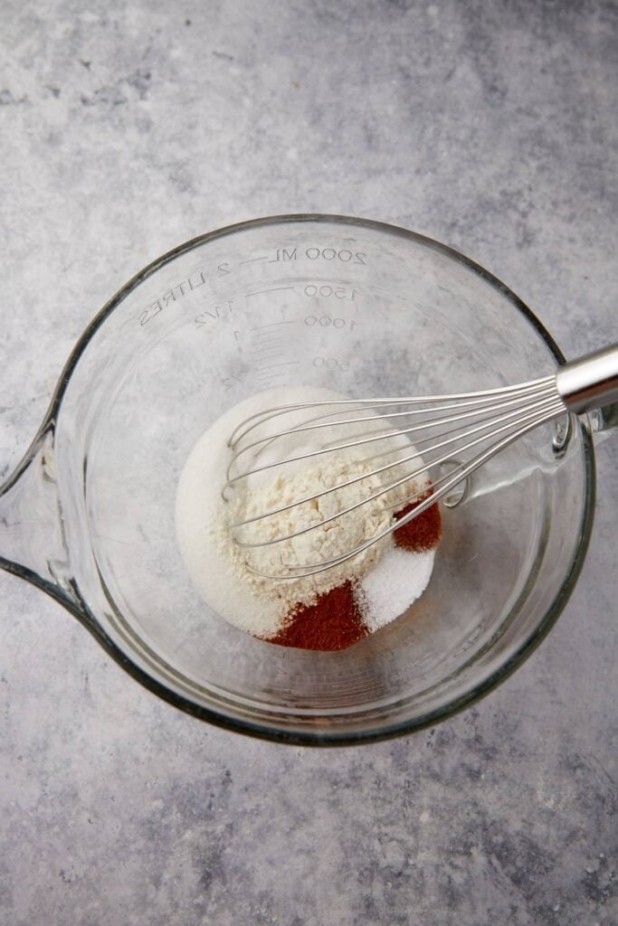 Dry ingredients for buttermilk pie are measured in a bowl with cinnamon and flour visible.