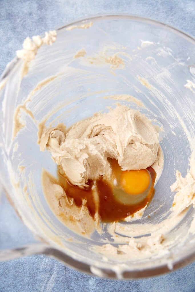 Mixing bowl with creamed butter and brown sugar, with an egg and vanilla added before mixing.