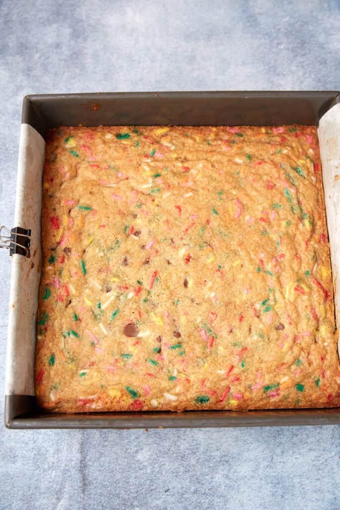 Baked sprinkle blondies in the pan with golden edges and colorful sprinkles visible across the top.