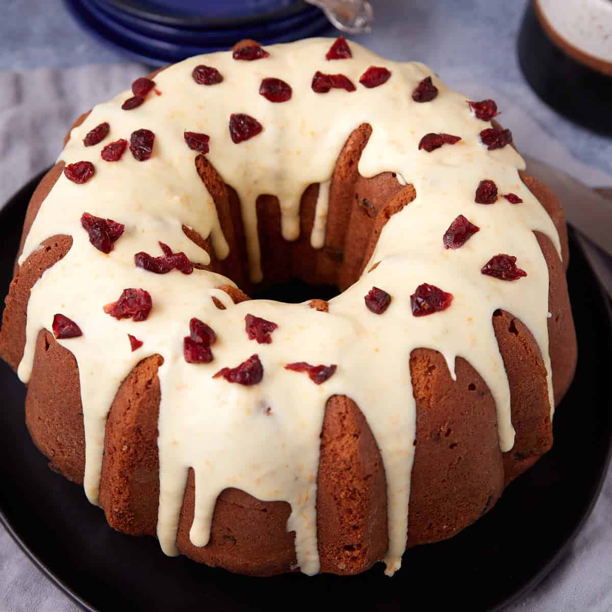 Close-up of the glazed cranberry orange bundt cake with dried cranberries scattered on top.