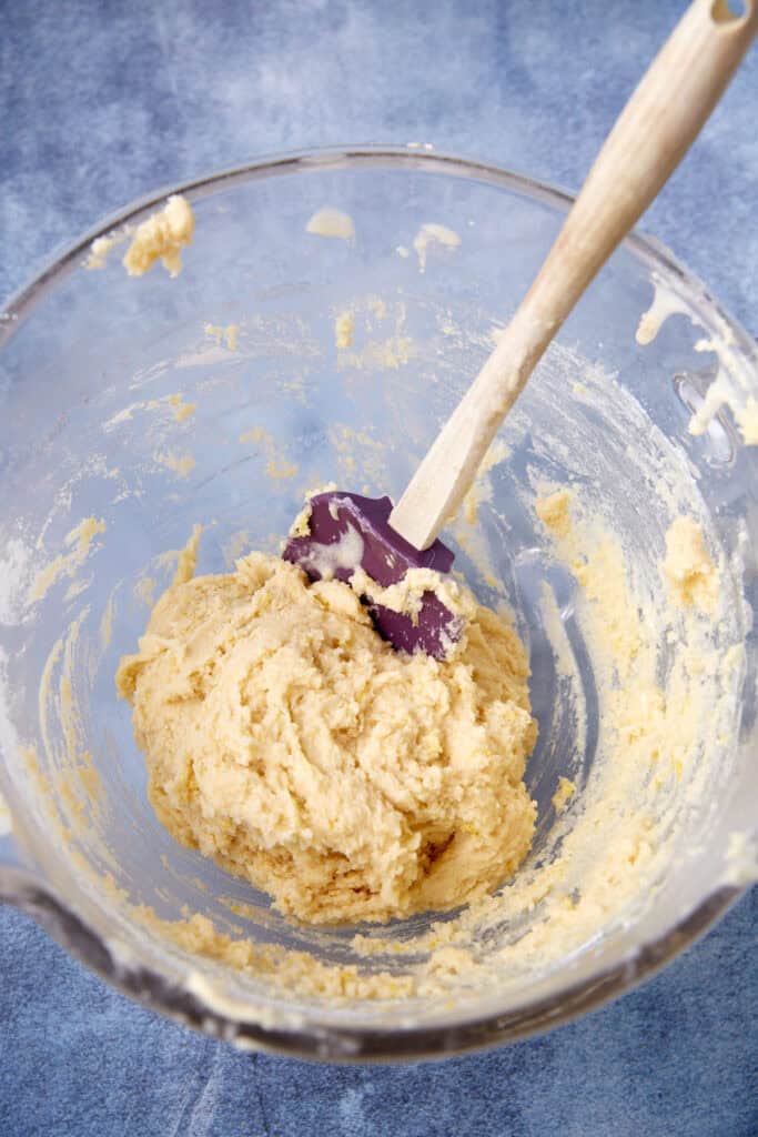 Mixing bowl with lemon cookie dough and a spatula, showing a soft, sticky dough texture.