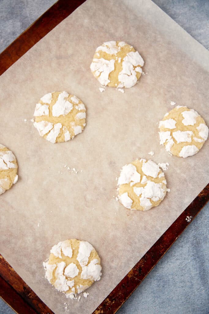 Powdered sugar lemon crinkle cookies cooling on a wire rack.