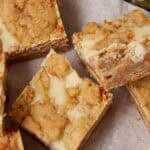 Carrot cake cheesecake bars arranged on a tray with the creamy cheesecake layer and carrot cake base visible.
