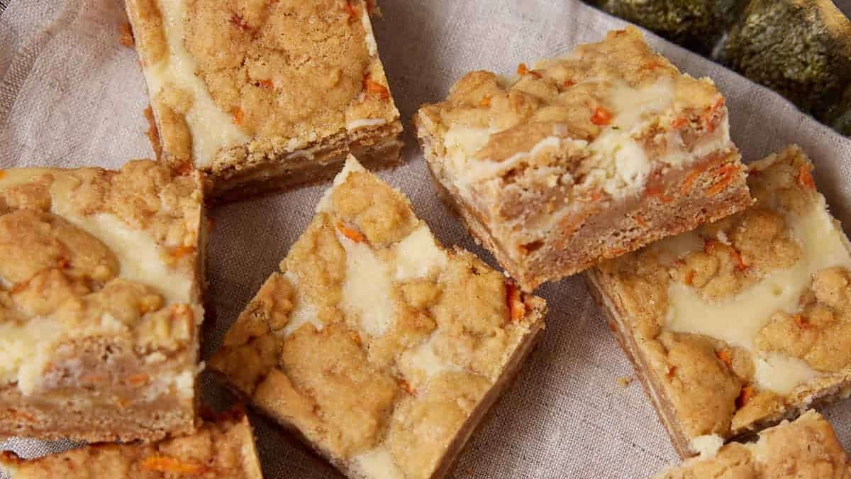 Carrot cake cheesecake bars arranged on a tray with the creamy cheesecake layer and carrot cake base visible.