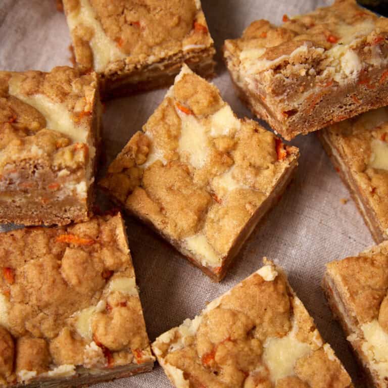 Close-up of carrot cake cheesecake bars cut into squares, showing the swirled carrot cake and cheesecake layers.