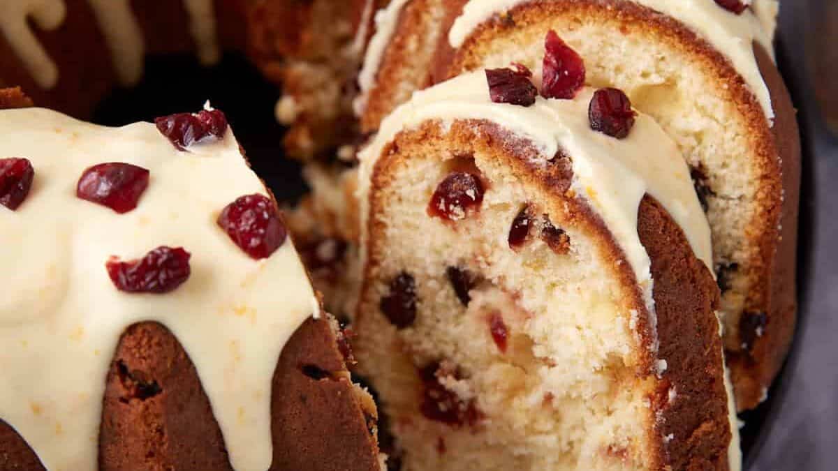 Sliced cranberry orange bundt cake shows the crumb and cranberries with glaze drizzled over the slices.
