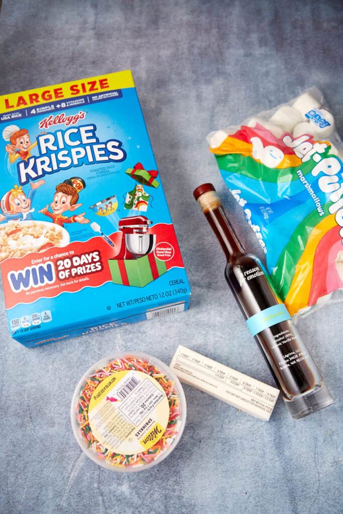 Rice Krispies cereal, marshmallows, vanilla, butter, and sprinkles arranged on a counter for making Rice Krispie treats with sprinkles.