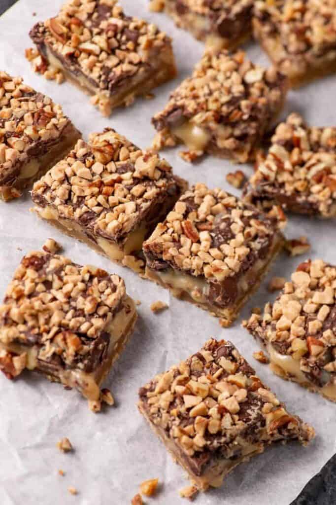 Shortbread toffee bars arranged on parchment paper, showing the gooey filling and chocolate topping.