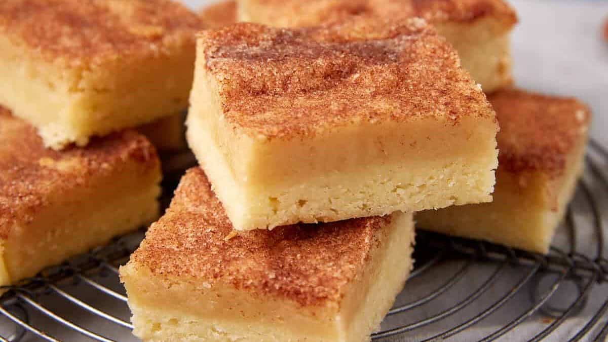 Close-up of layered snickerdoodle bars on a cooling rack, showing the distinct cookie base and soft top layer.