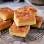 Layered snickerdoodle bars stacked on a cooling rack with a cinnamon sugar top.